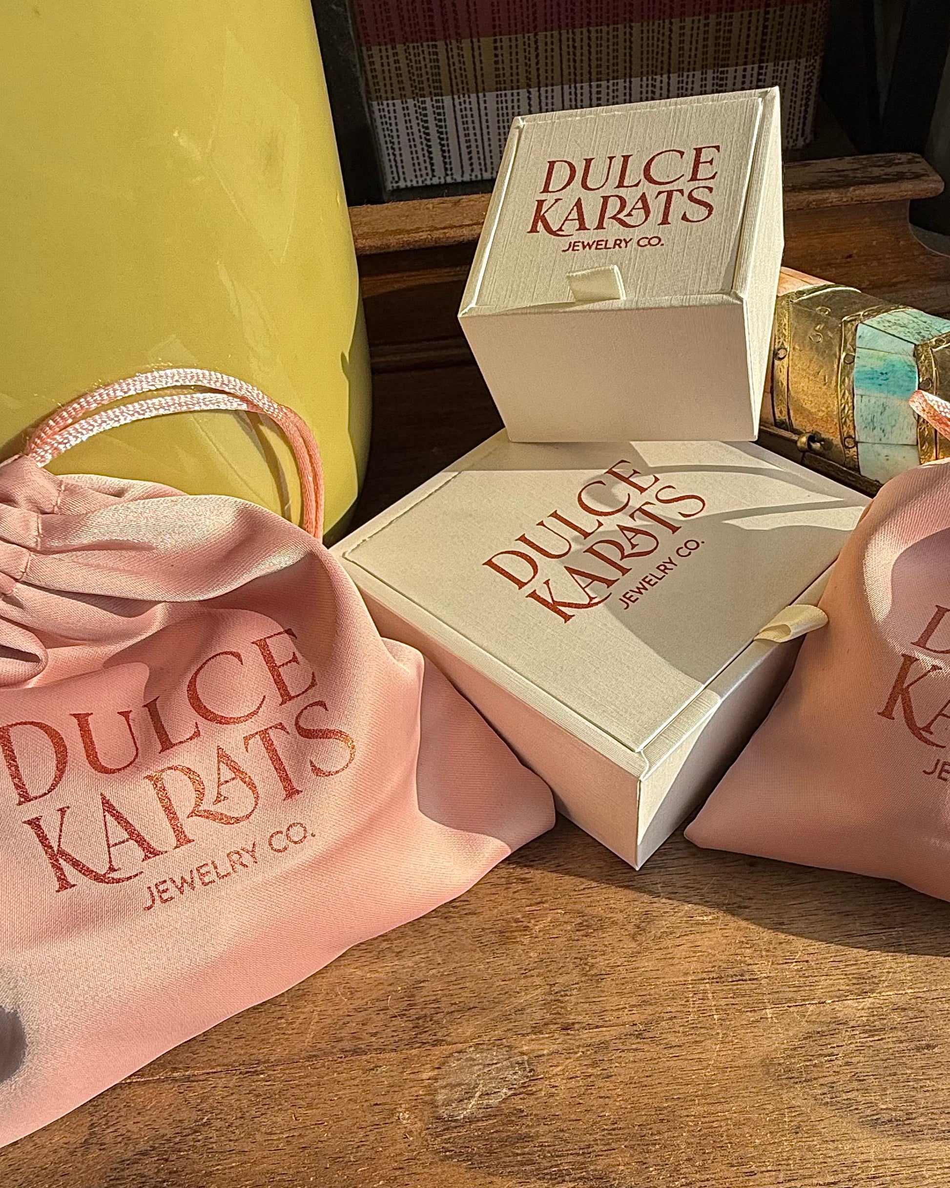 Dulce Karats jewelry boxes and bags on a wooden surface