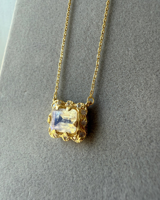 Gold necklace with a clear gemstone on a gray background