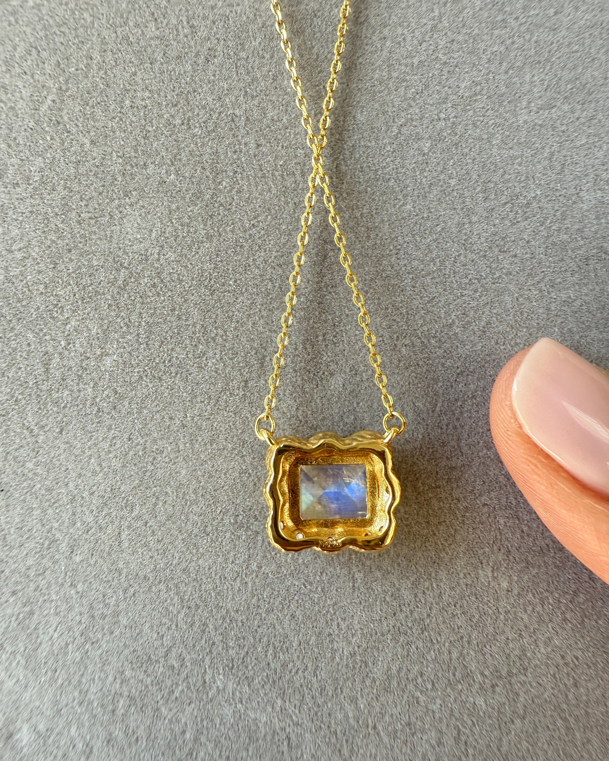 Gold necklace with a pendant on a gray surface